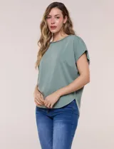 Remera de silueta amplia y relajada confeccionada en algodón y poliéster, de color verde, con escote a la base y mangas cortas de hombro caído. Presenta dobladillo enrollado y ruedo curvo.