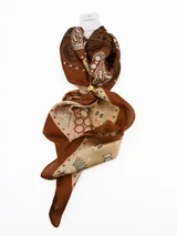 Pañuelo de seda con estampado geométrico en blanco, negro y gris, que incluye un anillo metálico dorado para sujetarlo.