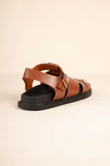 Sandalias bajas tipo gladiador, color negro, con tiras entrelazadas y hebilla metálica ajustable.