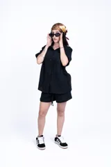 Camisa negra de manga corta con cuello clásico, bolsillo en el pecho y corte holgado.