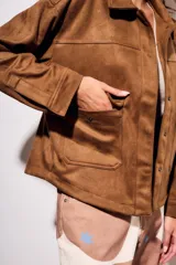 Sobrecamisa marrón de gamuza sintética, con cuello camisero, cierre frontal con botones, mangas largas con puños abotonados y bolsillos de parche en el pecho.