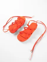 Sandalias con plataforma color naranja, tiras finas y ajuste con cordones al tobillo.