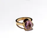 Anillo dorado con piedra rosa clara en su frente.