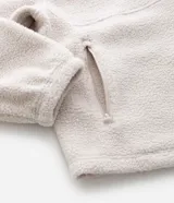Campera deportiva de sherpa color beige, con cuello alto, cierre frontal completo y bolsillo con cierre en el pecho. Presenta un corte boxy holgado, mangas largas y acabado de textura suave.