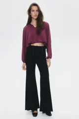 Blusa color vino tinto, con cuello redondo y escote en V con cordones para atar. Presenta mangas globo largas y un bajo fruncido con efecto burbuja.