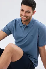 Remera polo de piqué de algodón color azul, de manga corta, con cuello camisero, cierre frontal de dos botones y pequeño logo bordado en el pecho.