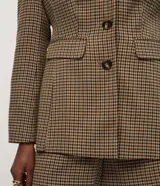 Blazer de sastrería con estampado pied de poule, corte estructurado, cuello con solapa clásica, cierre frontal de tres botones y bolsillos con solapa.