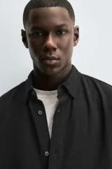 Camisa de corte regular fit confeccionada en tejido de algodón con textura de cuadrillé. Presenta cuello solapa, manga larga con puños abotonados y cierre frontal mediante botonadura.