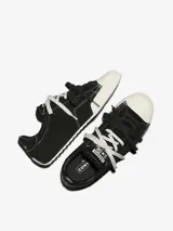 Championes Converse Chuck Taylor Low Top de ante premium color negro, con puntera de goma blanca, detalles de costuras visibles y cordones intercambiables.
