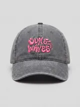 Gorra con visera de lona lavada color gris con efecto acid wash, con bordado frontal en relieve color rosado con la frase "Sun & Waves".