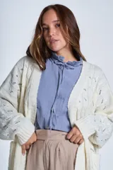 Sacón de hilado frizado color crudo, con calado delicado y bolsillos tejidos al frente. De corte relajado.