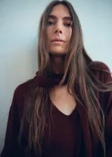 Jersey de punto fino color bordó, con cuello en pico y detalle de fular integrado en el escote. Presenta un diseño recto de manga larga.