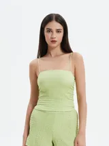 Musculosa verde con textura arrugada y tirantes finos.