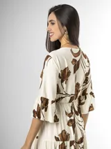 Vestido largo color crudo con estampado floral marrón, escote en V cruzado, mangas tres cuartos con volados y falda con niveles fruncidos.