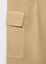 Pantalon cargo de lino color beige, con tiro medio, cintura elástica con lazo ajustable, bolsillos de parche con solapa en los laterales y corte recto.