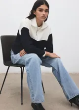 Jersey de punto de manga larga, con diseño bicolor en blanco y negro, cuello alto con cierre de cremallera corta.