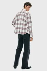 Camisa de franela de algodón suave con efecto lavado, de corte relajado y cuello inglés. Presenta un estampado a cuadros en blanco, rojo y negro, tapeta clásica de botones, un bolsillo superior abierto y canesú en la espalda. Tiene mangas largas con tapeta, puños abotonados y bajo levemente redondeado.