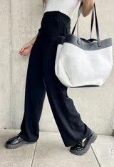 Pantalón negro de lino, de corte ancho y largo, con diseño suelto y botones decorativos en la cintura.