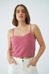 Top corto de dama con tirantes finos ajustables, confeccionado en tejido de textura natural con costuras decorativas en el frente y grifa de cuero.