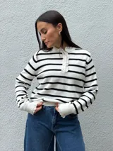 Sweater de punto a rayas horizontales blancas y negras, con cuello redondo, cierre frontal con botones y detalles de puntilla en el cuello y los puños.