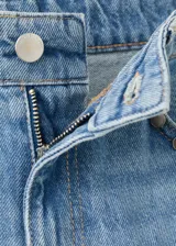 Jeans de denim celestes de tiro medio, diseño de corte recto y amplio con detalles de tachuelas en los bolsillos delanteros.