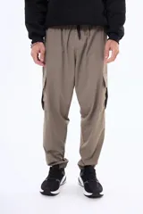 Pantalón cargo de corte holgado en color beige, con cintura elástica, cordón de ajuste y bolsillos laterales con solapa. Presenta puños elásticos en los tobillos.