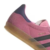 Championes adidas Gazelle Indoor de gamuza en color rosado con las icónicas tres tiras laterales en negro. Presenta un diseño clásico de perfil bajo con suela de goma translúcida y detalle en el talón en color azul oscuro.