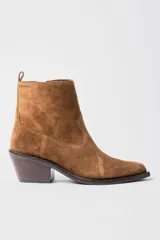 Bota corta de estilo western confeccionada en cuero gamuzado color marrón. Presenta un diseño de caña media con tirador trasero, corte asimétrico en el empeine, punta cuadrada y taco bloque de madera.