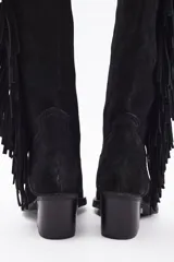 Bota bucanera de caña alta confeccionada en cuero vacuno, con diseño de estilo western que presenta flecos laterales largos y taco cuadrado.