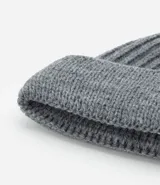 Gorro tipo fisherman de tejido acrílico con textura acanalada, diseño corto y etiqueta pequeña con logo en el frente.