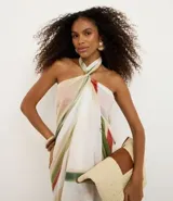 Pareo rectangular de chiffon con estampado botánico de hojas de buriti en tonos verdes, rojos y beige. Presenta un diseño ligero y versátil con detalle de borlas en los extremos.