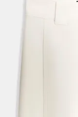 Pantalón de tiro medio en color crudo, con diseño de corte recto y trabillas en la cintura. Presenta cierre frontal con cremallera y gancho metálico.