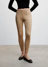 Leggings de efecto gamuza en color beige, con diseño ajustado, costuras frontales verticales y cierre lateral en el bajo.