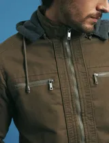 Campera técnica de tejido elástico en color azul marino, con capucha ajustable, cierre frontal y bolsillos laterales con cierre. Cuenta con forro interior de micro polar y ajuste en el ruedo.