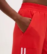Pantalón deportivo de corte recto y holgado, color rojo con doble raya lateral blanca. Cuenta con cintura elástica y bolsillos laterales.