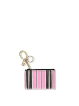 Estuche plegable para tarjetas y llavero con cierre de cremallera y diseño de rayas verticales en tonos rosados, negros y blancos. Incluye herrajes dorados y llavero con cadena y dijes colgantes.