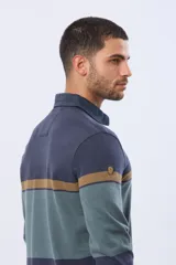 Remera polo de manga larga con diseño de bloques de color horizontales en tonos azul, verde y marrón. Presenta cuello clásico, cierre frontal con botones y bordado en el pecho. Cuenta con puños elásticos acanalados.