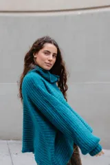 Buzo de tejido de punto en mezcla de lana y alpaca, color gris. Presenta una silueta amplia con cuello tipo polo que incluye broches para convertirlo en polera, mangas largas con puños y un diseño de tejido horizontal.
