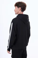 Buzo tipo canguro de felpa color negro, con capucha, bolsillo frontal tipo canguro, estampa frontal con texto y detalle de tres líneas blancas en las mangas.