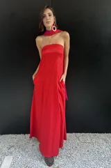 Vestido largo strapless con corpiño fruncido en color fucsia brillante y falda amplia en color rojo vibrante. La prenda tiene bolsillos laterales.