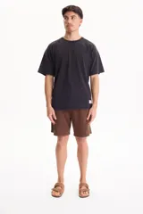 Remera oversize de manga corta raglán, color negro con efecto lavado acid wash, corte semi boxy y detalle de etiqueta lateral en el ruedo.