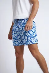 Short de baño con cintura elástica y cordón ajustable, confeccionado en tela ligera de secado rápido. Presenta un estampado botánico integral en tonos amarillos, blancos y azules, con dos bolsillos delanteros y uno posterior.