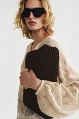 Bolso tipo sobre color marrón, con cuerpo trenzado y asa de mano rígida dorada. Incluye correa bandolera de cadena extraíble y cierre magnético.