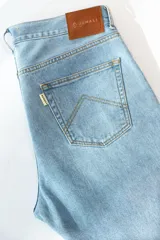 Jean de corte recto clásico con cinco bolsillos, botones de cobre y costuras color camel.