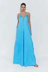 Mono largo celeste de lino, con tirantes finos, escote en V, cierre frontal con cremallera metálica, bolsillos laterales y pernera ancha.