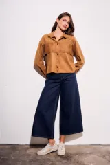 Camisa color camel de gamuza sintética, corte al cuerpo, con flecos en el pecho y mangas largas.