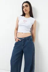 Pantalón de jean ancho color negro, de tiro bajo y confeccionado en algodón. Cuenta con una línea bordada color marrón en ambas piernas y cinco bolsillos.