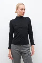 Remera blanca de media polera con mangas largas y volados en los puños.