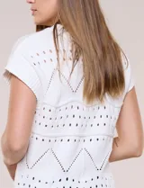 Buzo de tejido de algodón color blanco, de silueta semi holgada, con motivos de calados geométricos y guardas en zigzag. Cuenta con escote redondo, mangas cortas estilo japonesa y terminaciones acanaladas.