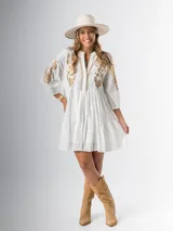 Vestido corto blanco de algodón italiano con bordado azul, mangas tres cuartos y botones frontales. Tiene forro interior en la falda.